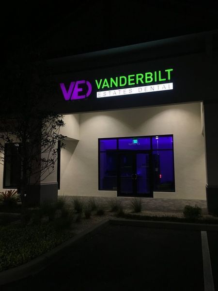 Exterior night view of Vanderbilt Dentistry office with illuminated green and purple signage.