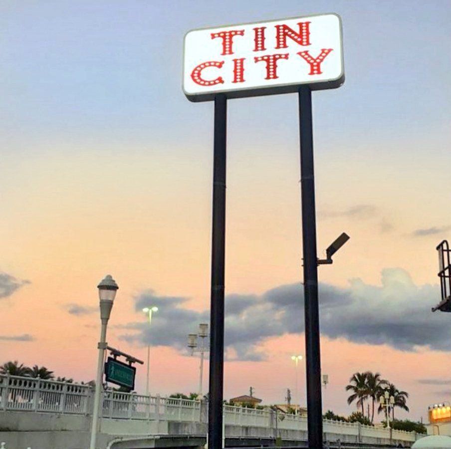 Sign for Tin City under a colorful sunset.