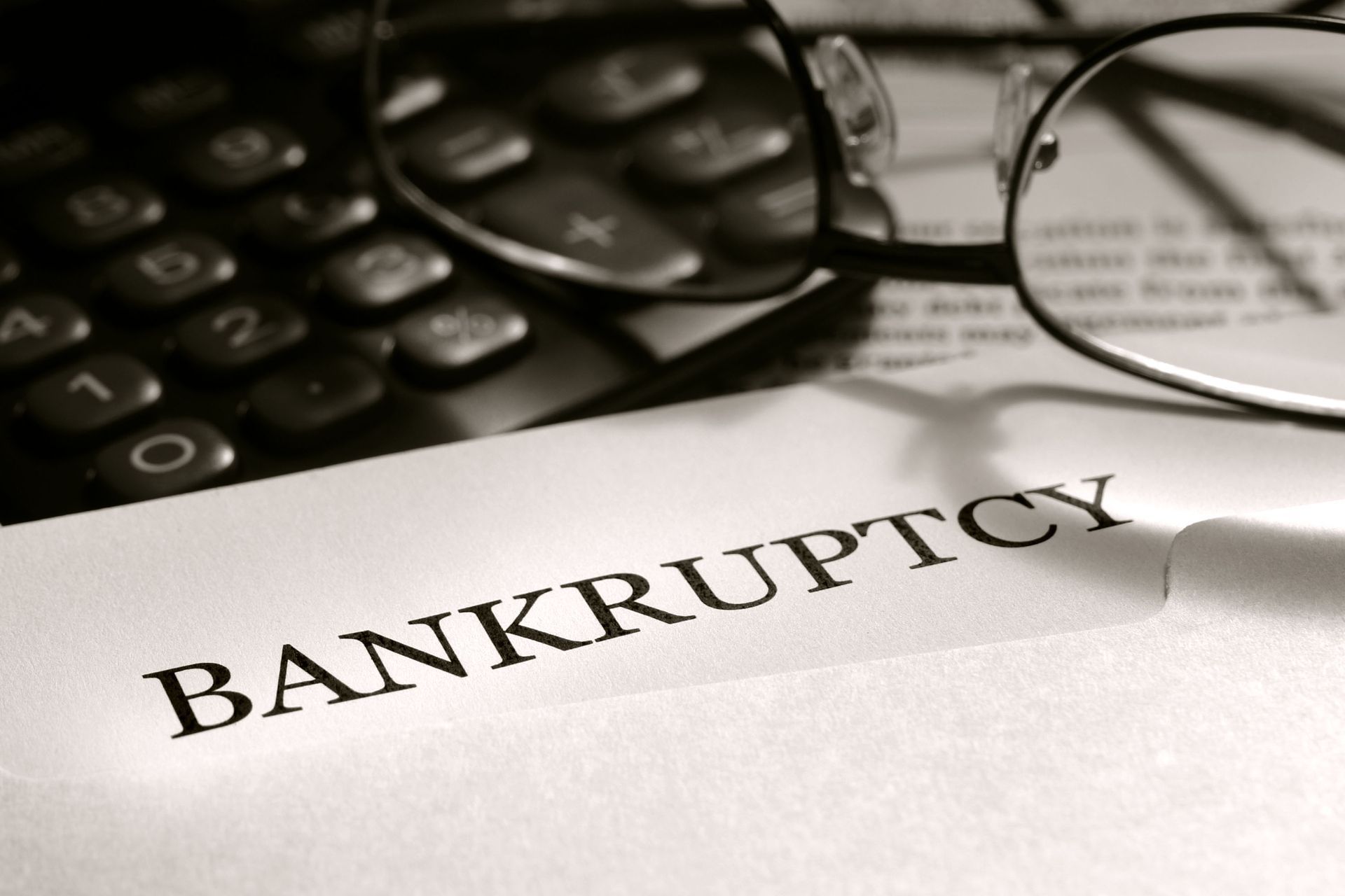 Bankruptcy document beside calculator and eyeglasses on a desk