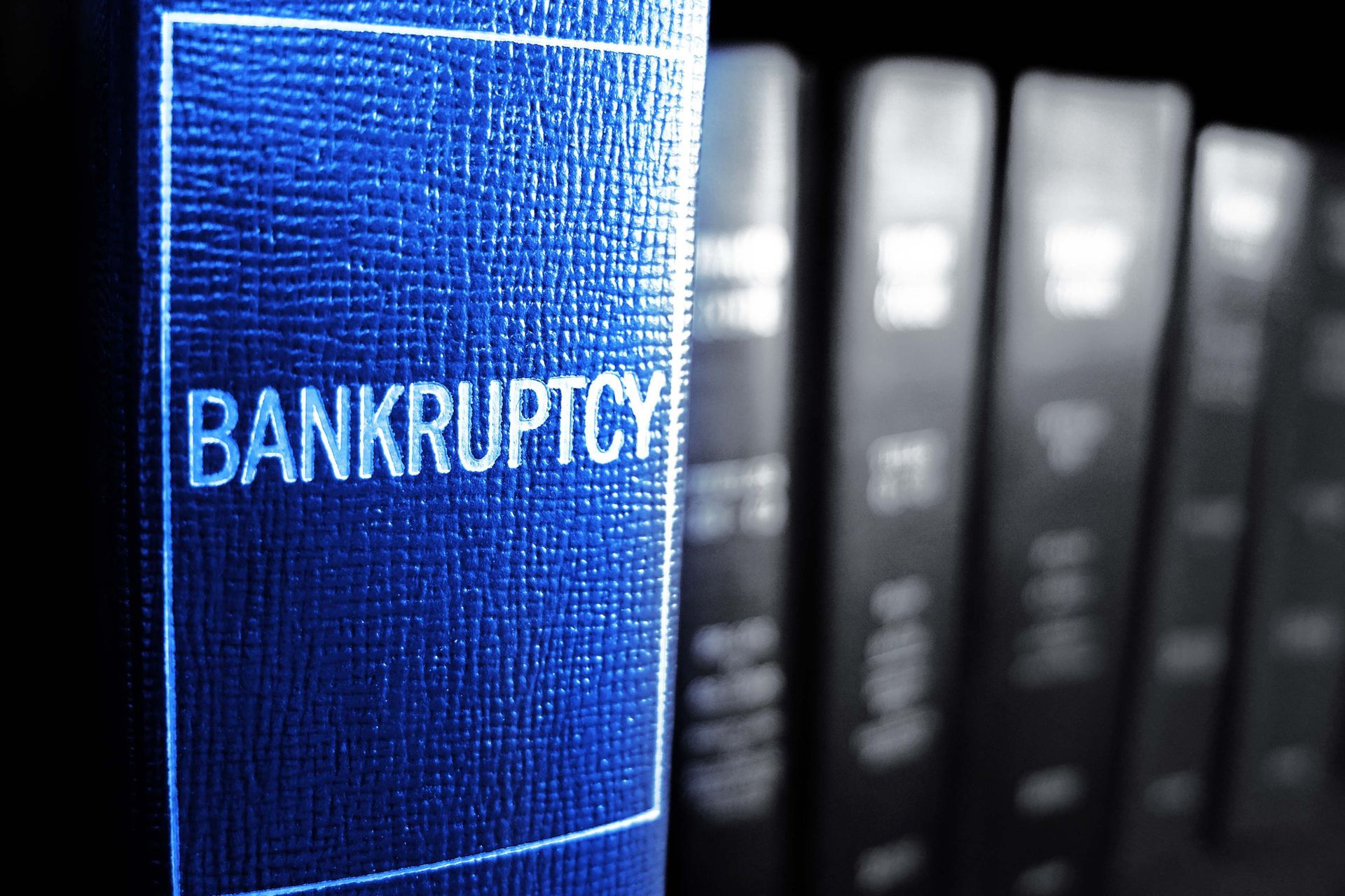 Blue book labeled “BANKRUPTCY” on a shelf, with blurred law books in the background