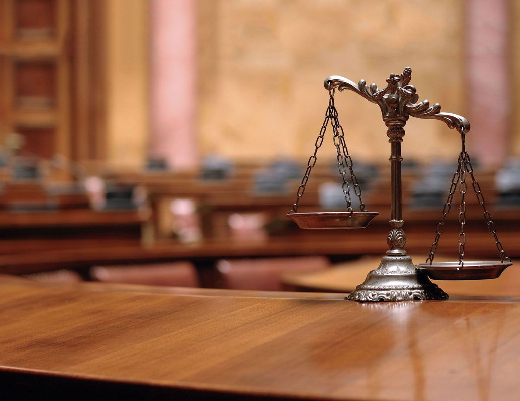 Close-up of a brass scales of justice on a wooden table in a courtroom