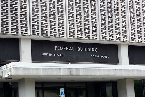 Federal building entrance with a black sign and patterned concrete facade.