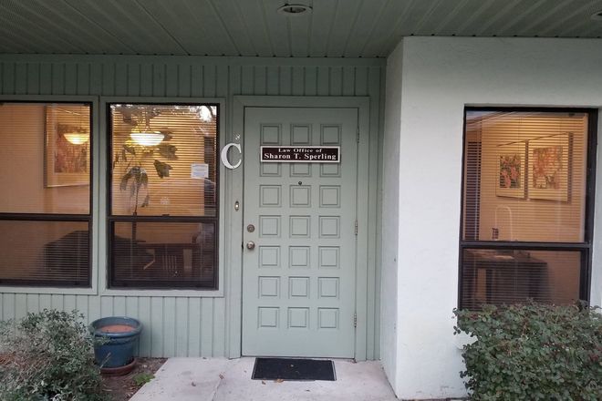 Front porch with a light green door, two windows, and a white column in front of a house.