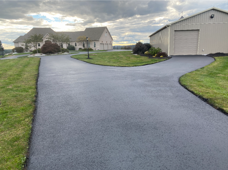 A driveway leading to a house with a garage in the background.