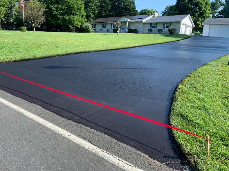 A driveway with a red line on it and a house in the background