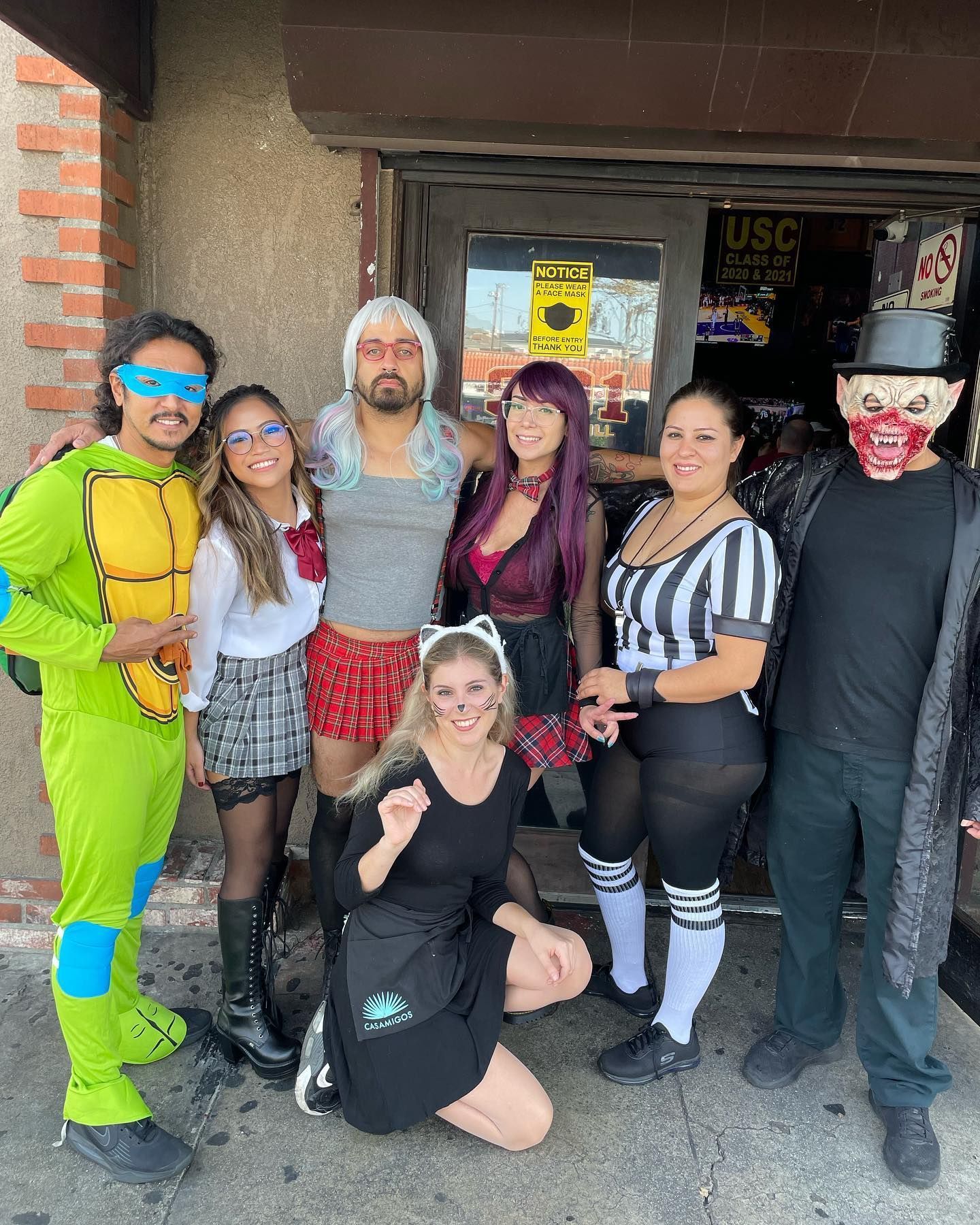 A group of people in costumes are posing for a picture in front of a building.