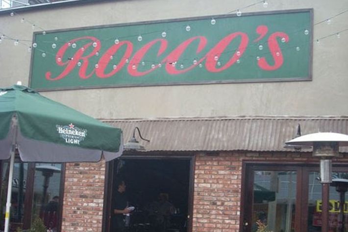 A brick building with a green sign that says rocco 's