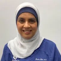The woman is wearing a hijab and smiling for the camera.