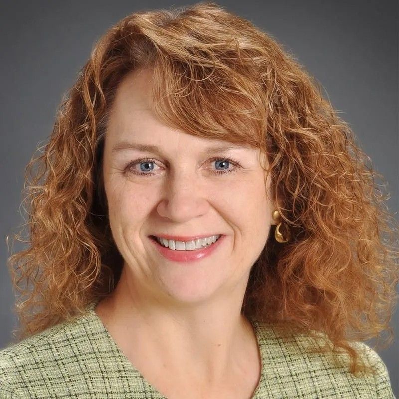A woman with red hair and blue eyes smiles for the camera