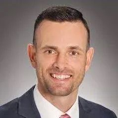 A man in a suit and tie is smiling for the camera.