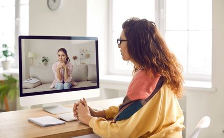 A woman is sitting at a desk looking at a computer screen.