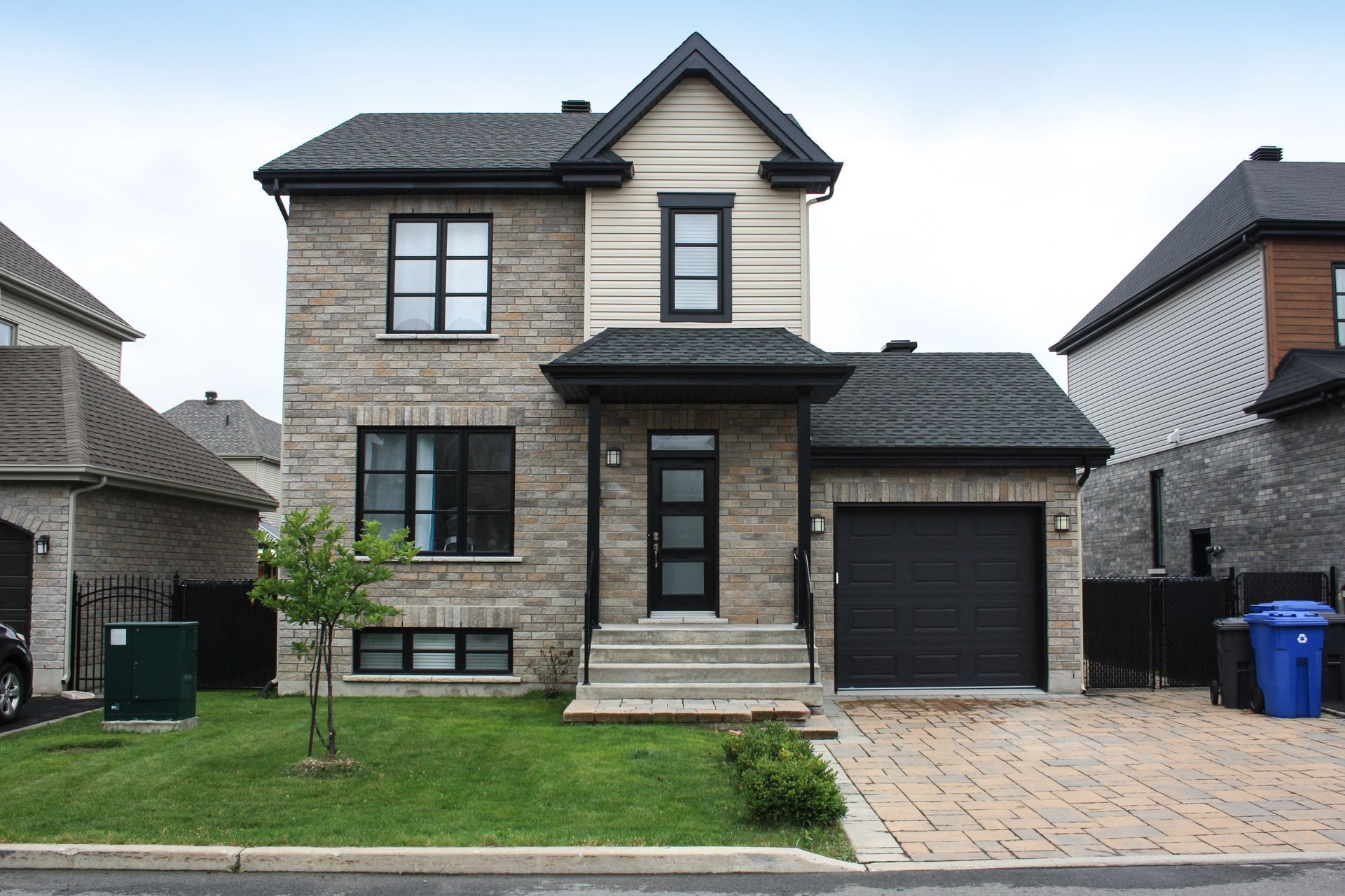 A two-story suburban house with stone siding, a dark roof, a front porch, and an attached one-car garage.
