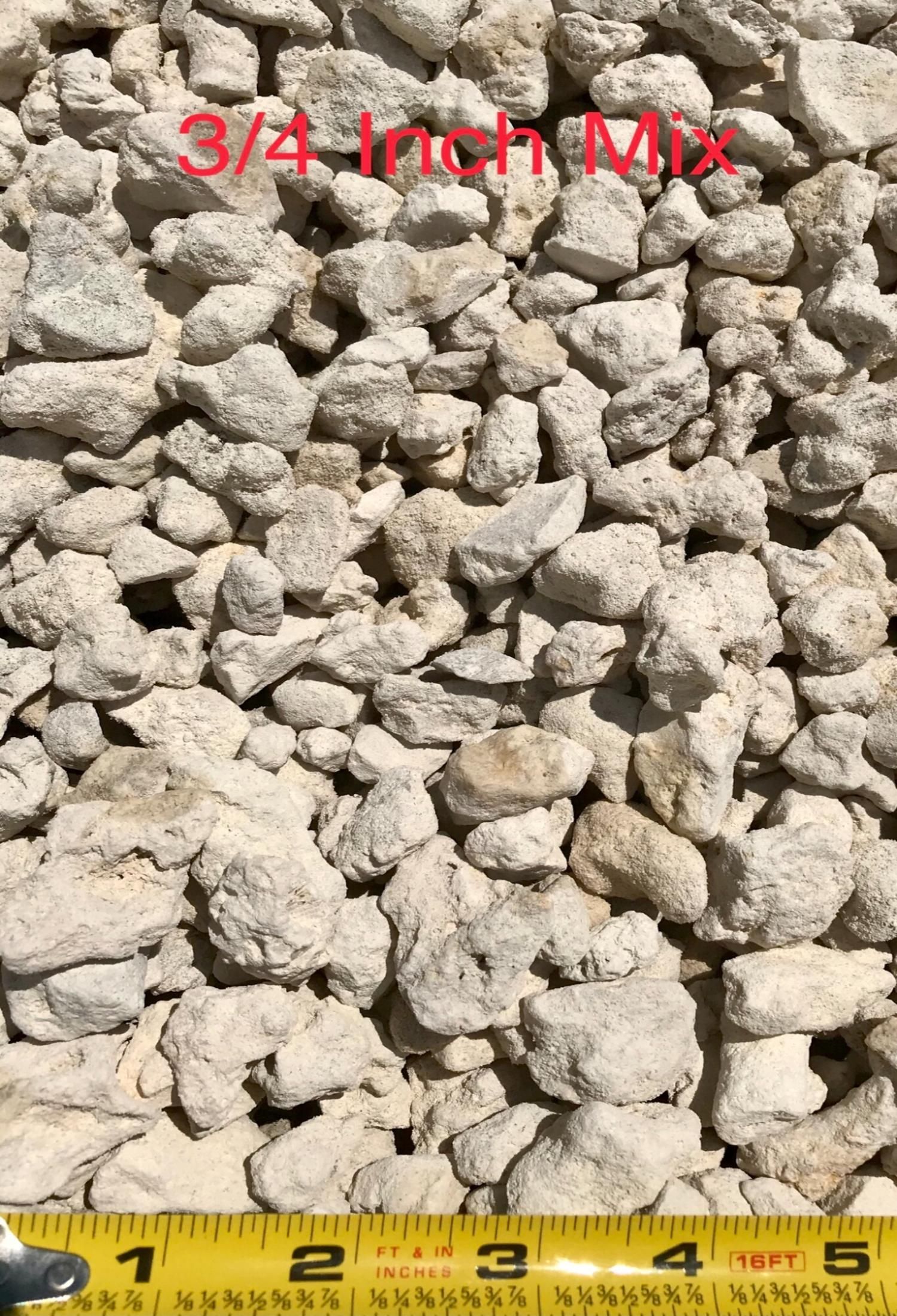 Close-up of gray 3/4-inch crushed stone with red label and yellow measuring tape at bottom