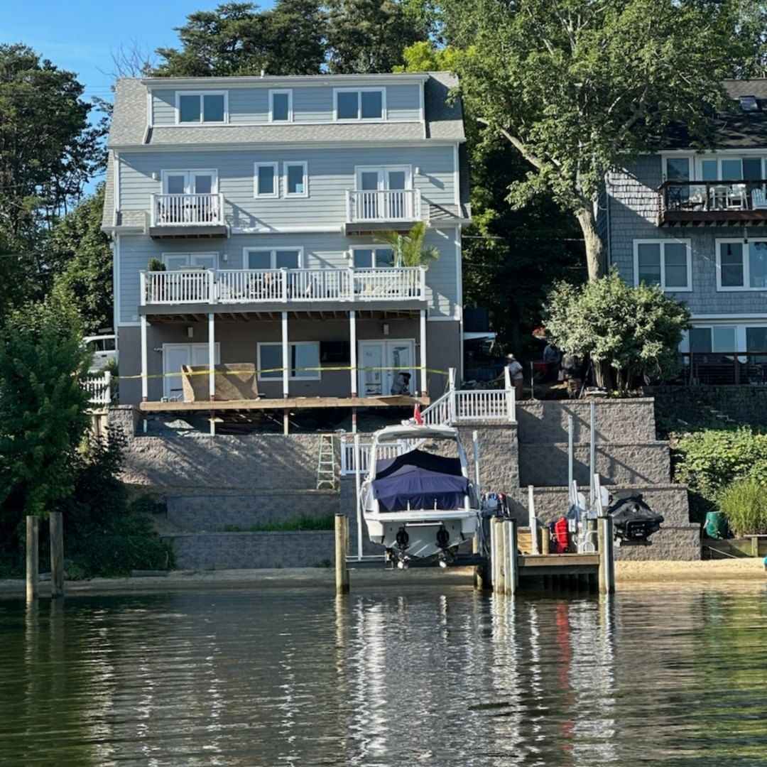 Lakefront gray house with balconies and a docked boat on calm water