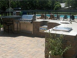 Outdoor patio with a built-in grill, hot tub, and swimming pool in the background.