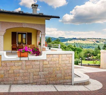 House with flowered porch overlooking a sunny rural landscape