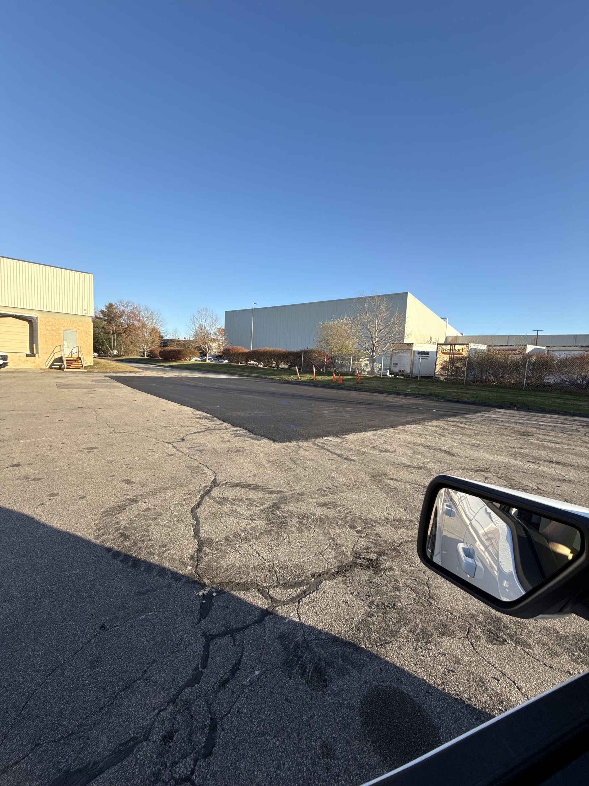 A car is driving down a road with a large building in the background.