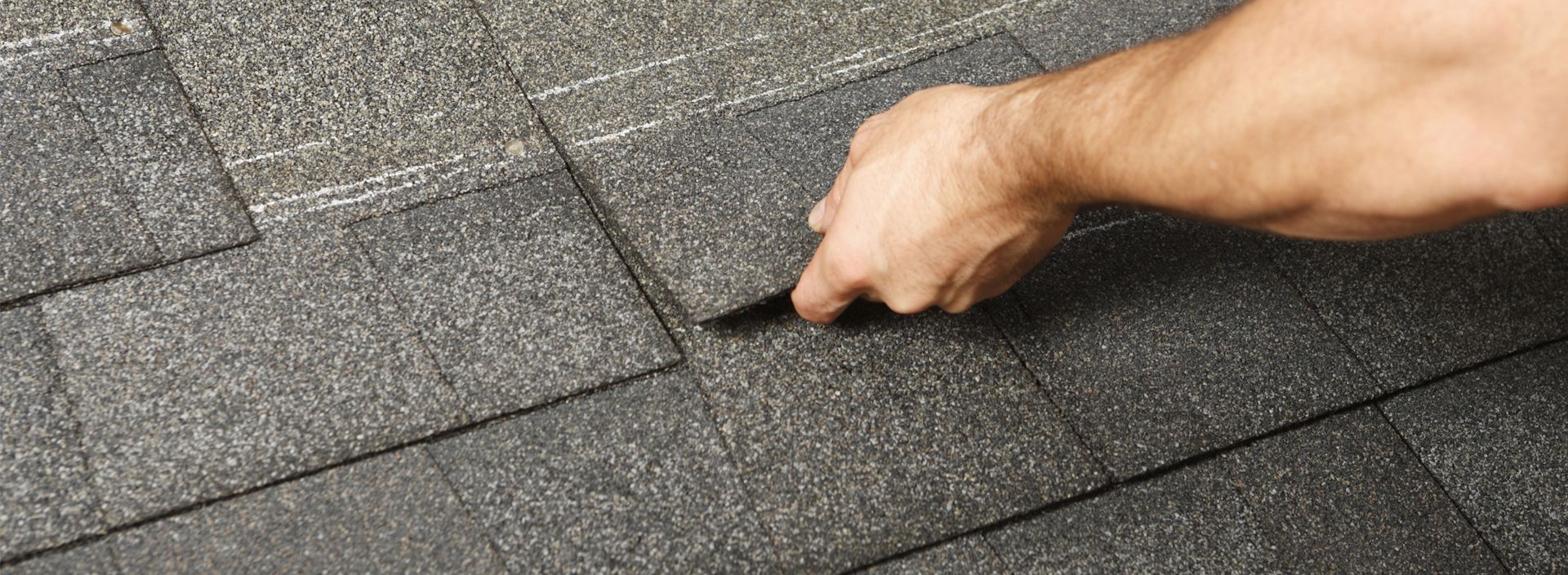 A person is installing roof shingles