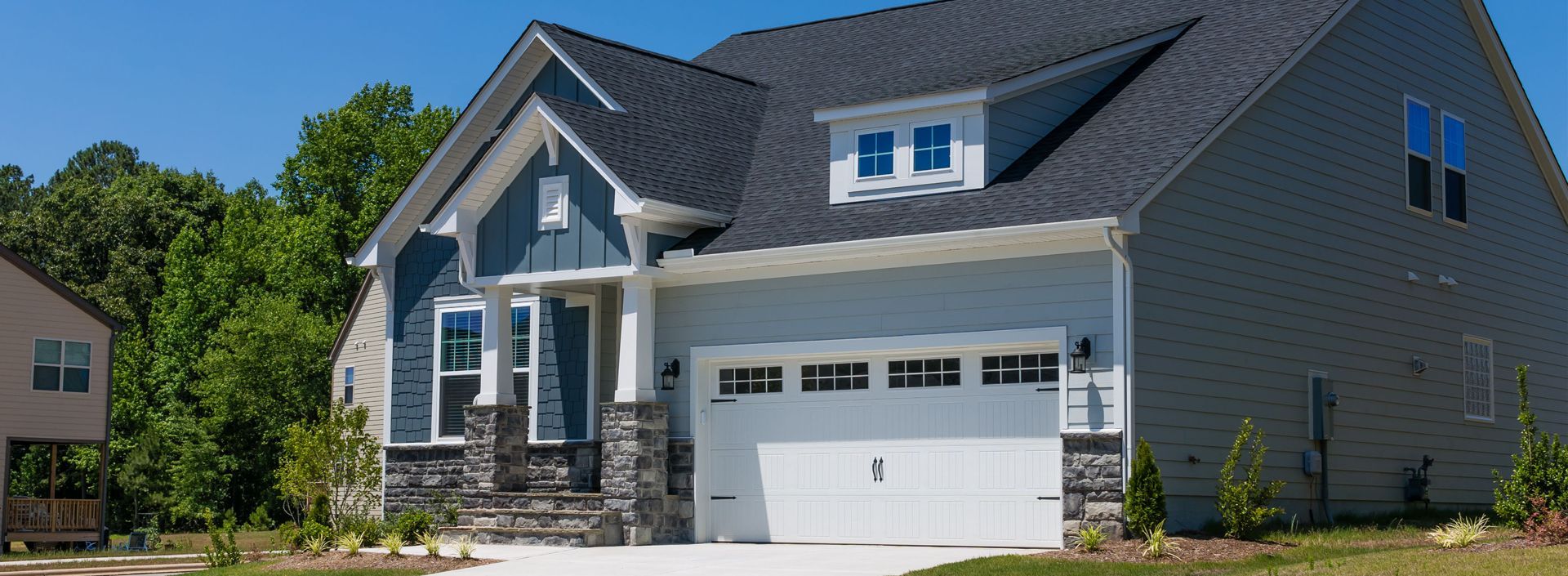 A large house with a gray roof and a white garage door