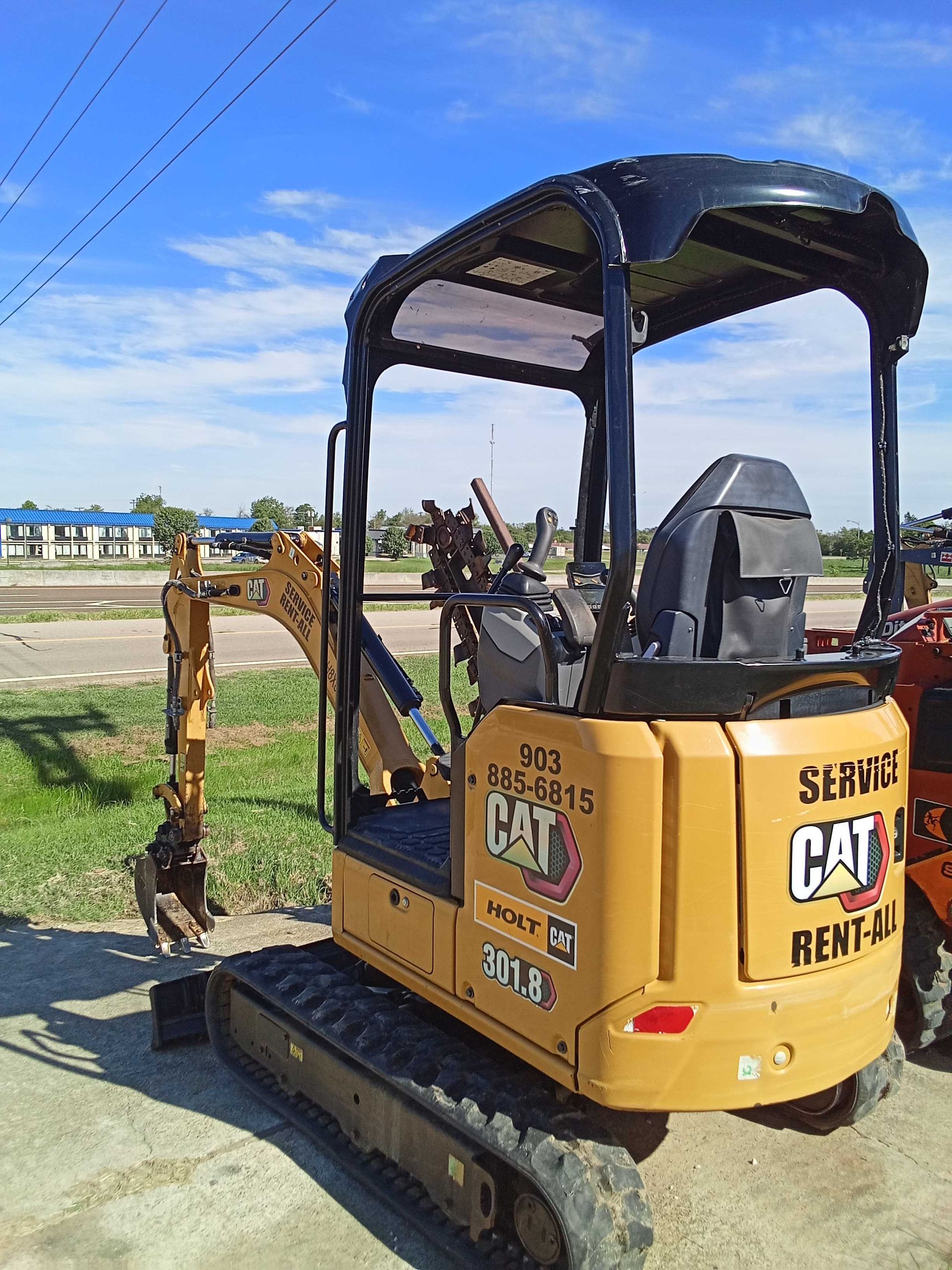 Yellow CAT mini excavator with black canopy on a sunny day.