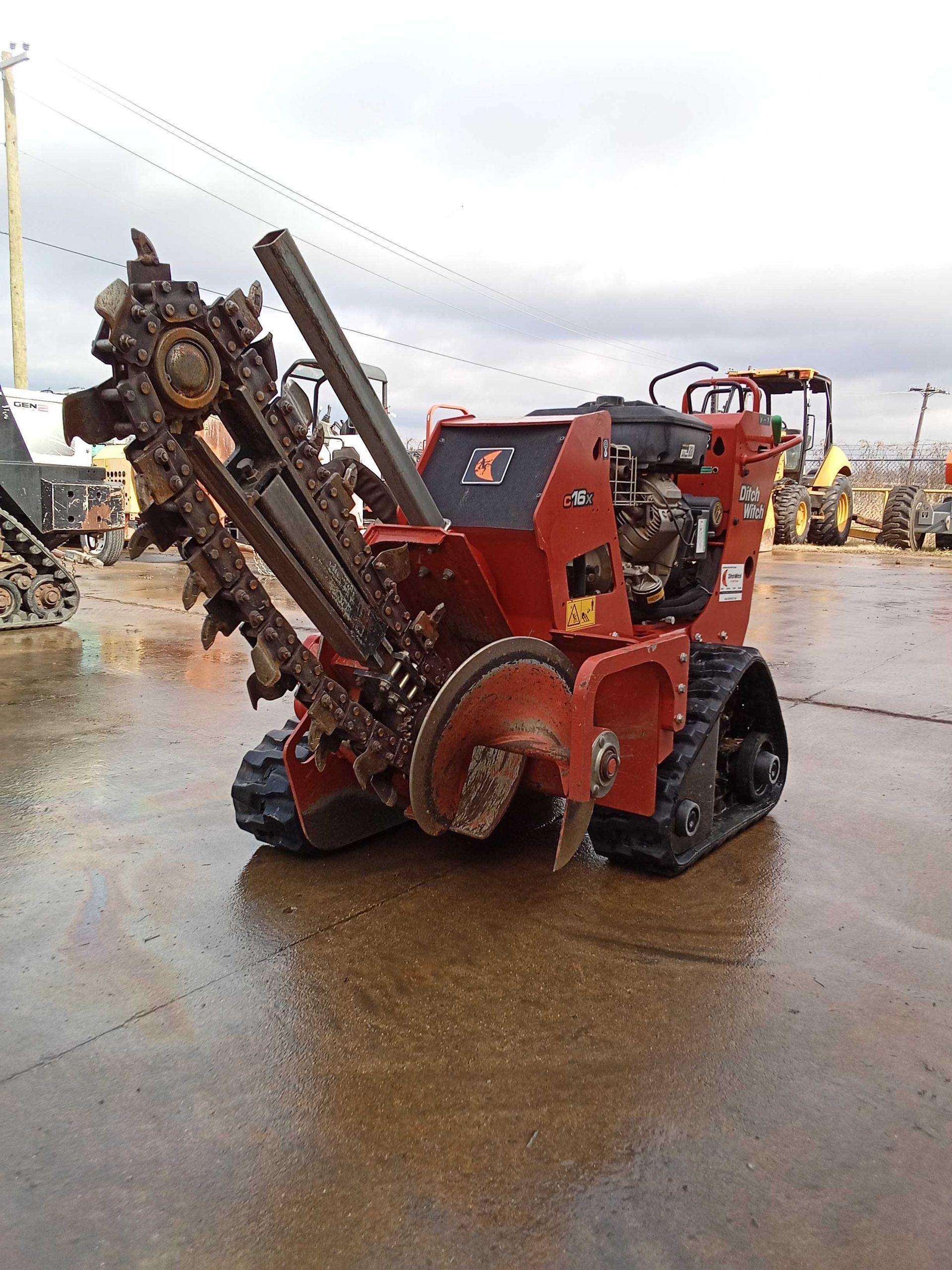 Red tracked trencher machine, outdoors on a wet surface.