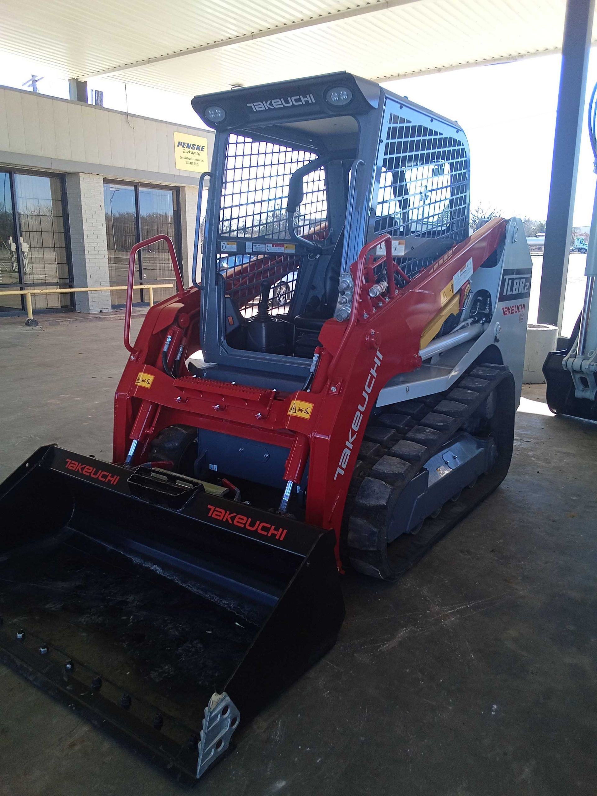 Red and gray skid steer loader with black bucket.