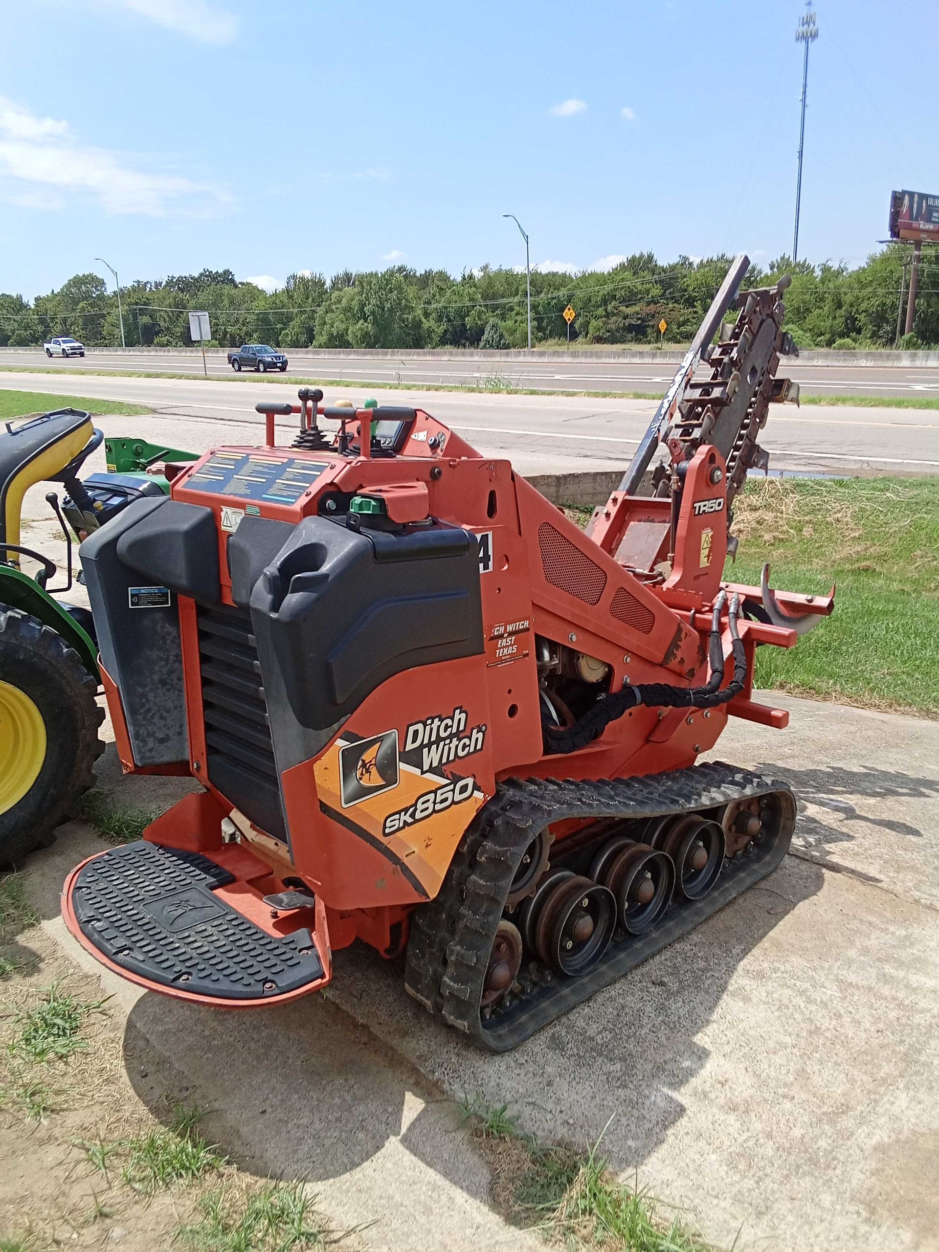 Orange Ditch Witch C160 trencher with tracks. Outdoors on concrete, daytime.