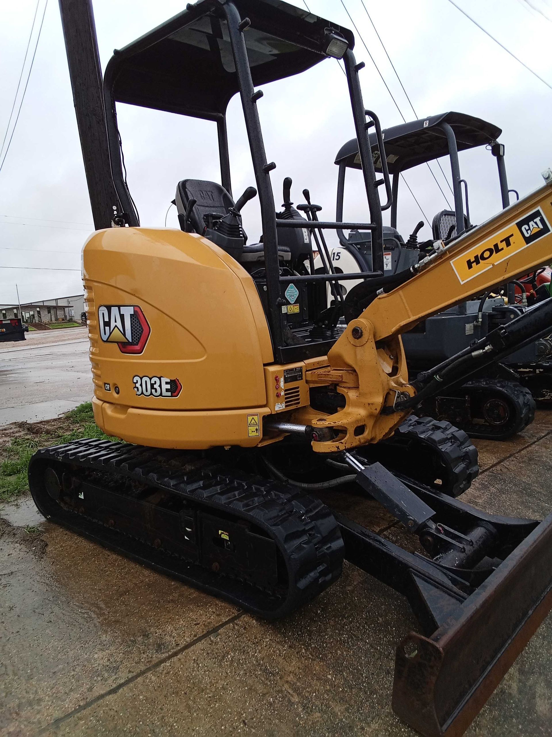Yellow Caterpillar 303E excavator with black tracks and a bucket.