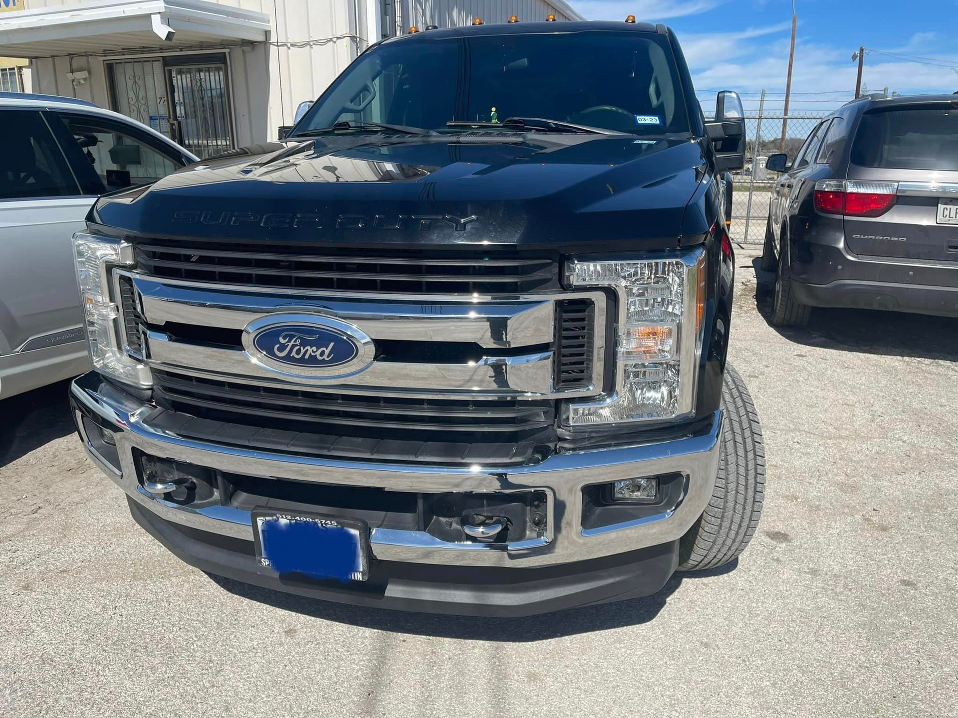 A black ford truck is parked in a parking lot next to other cars.