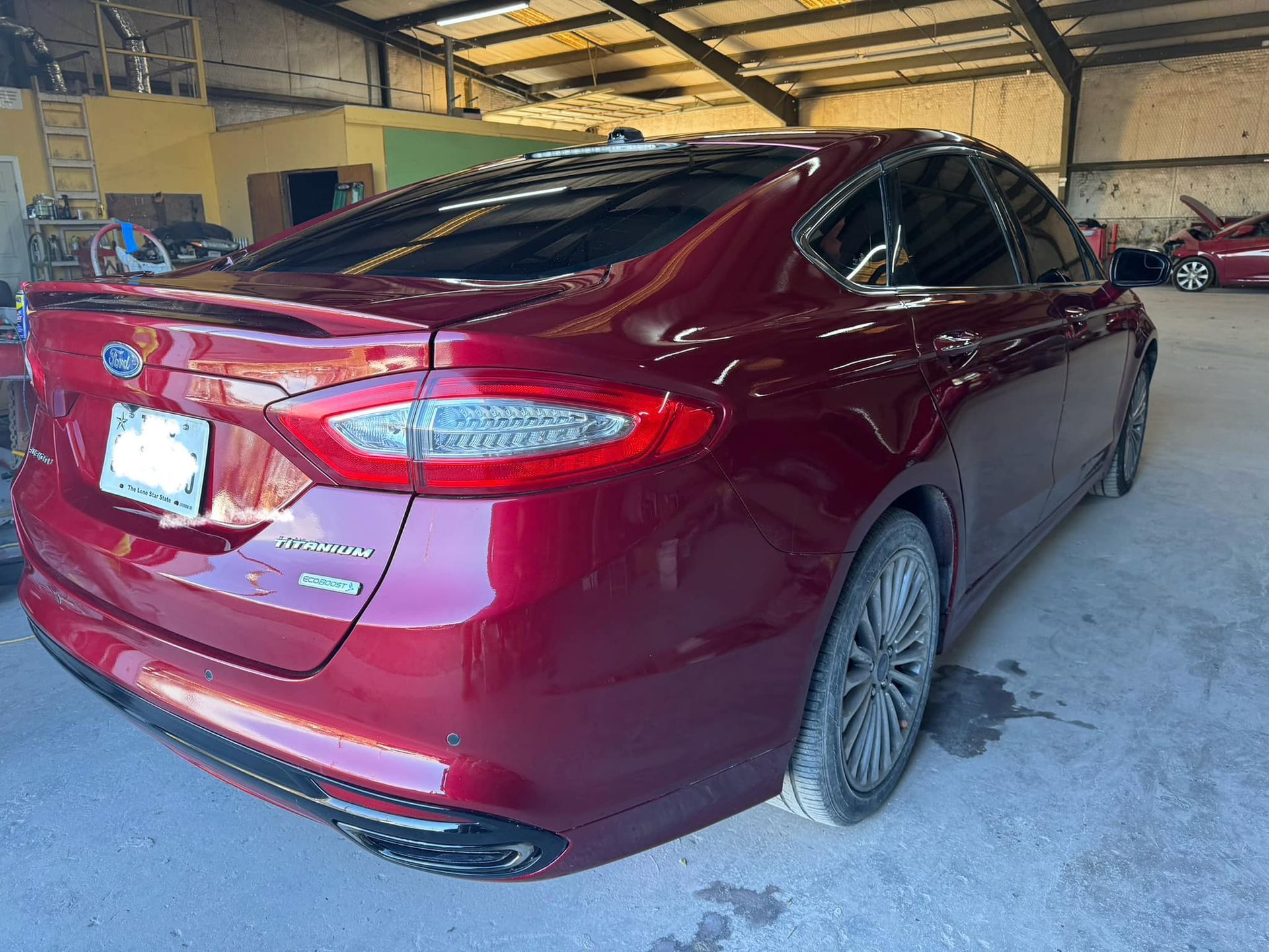 A red ford fusion is parked in a garage.