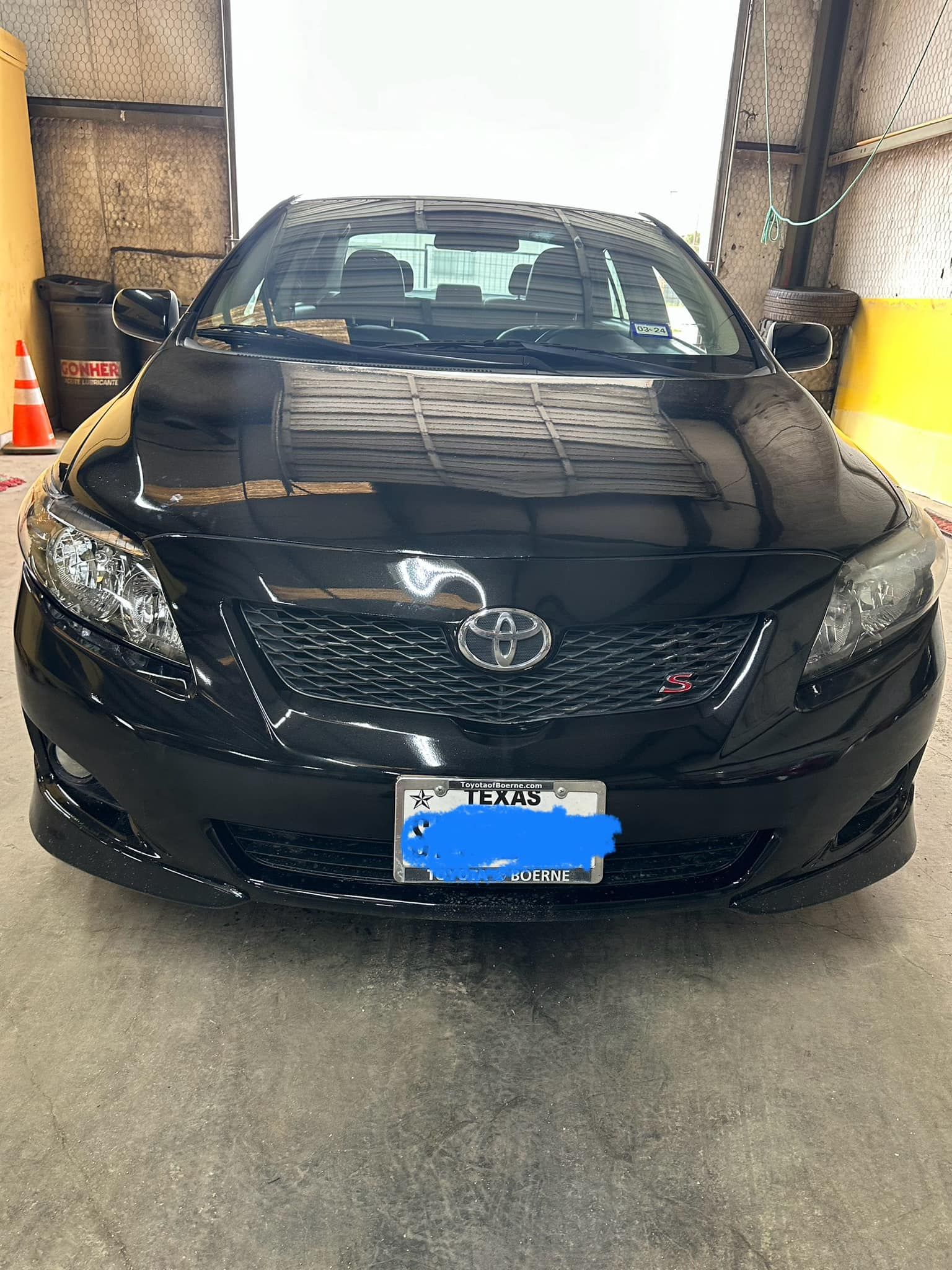 A black car with a license plate that says toyota is parked in a garage.