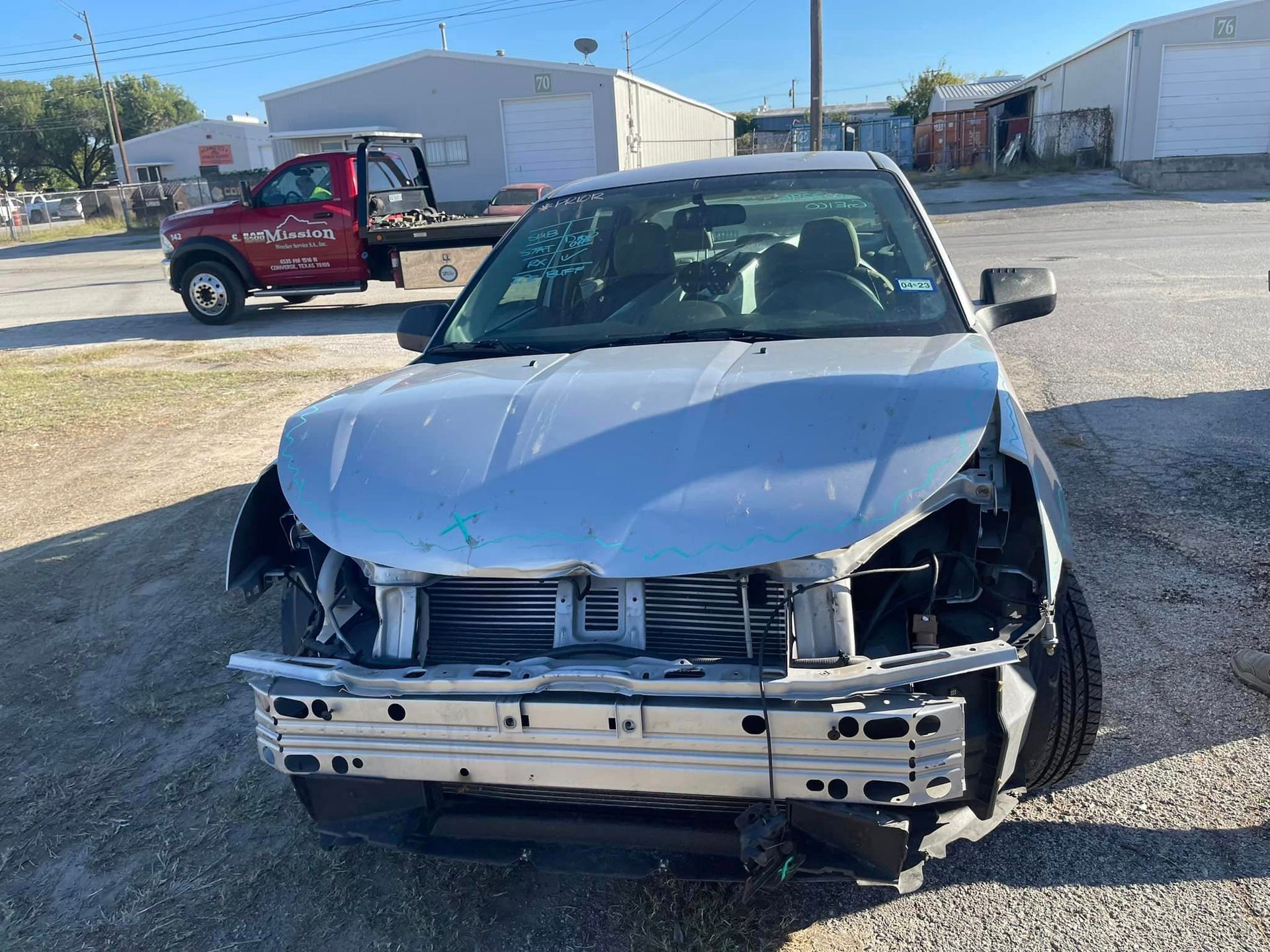 A damaged car is sitting in a parking lot next to a tow truck.
