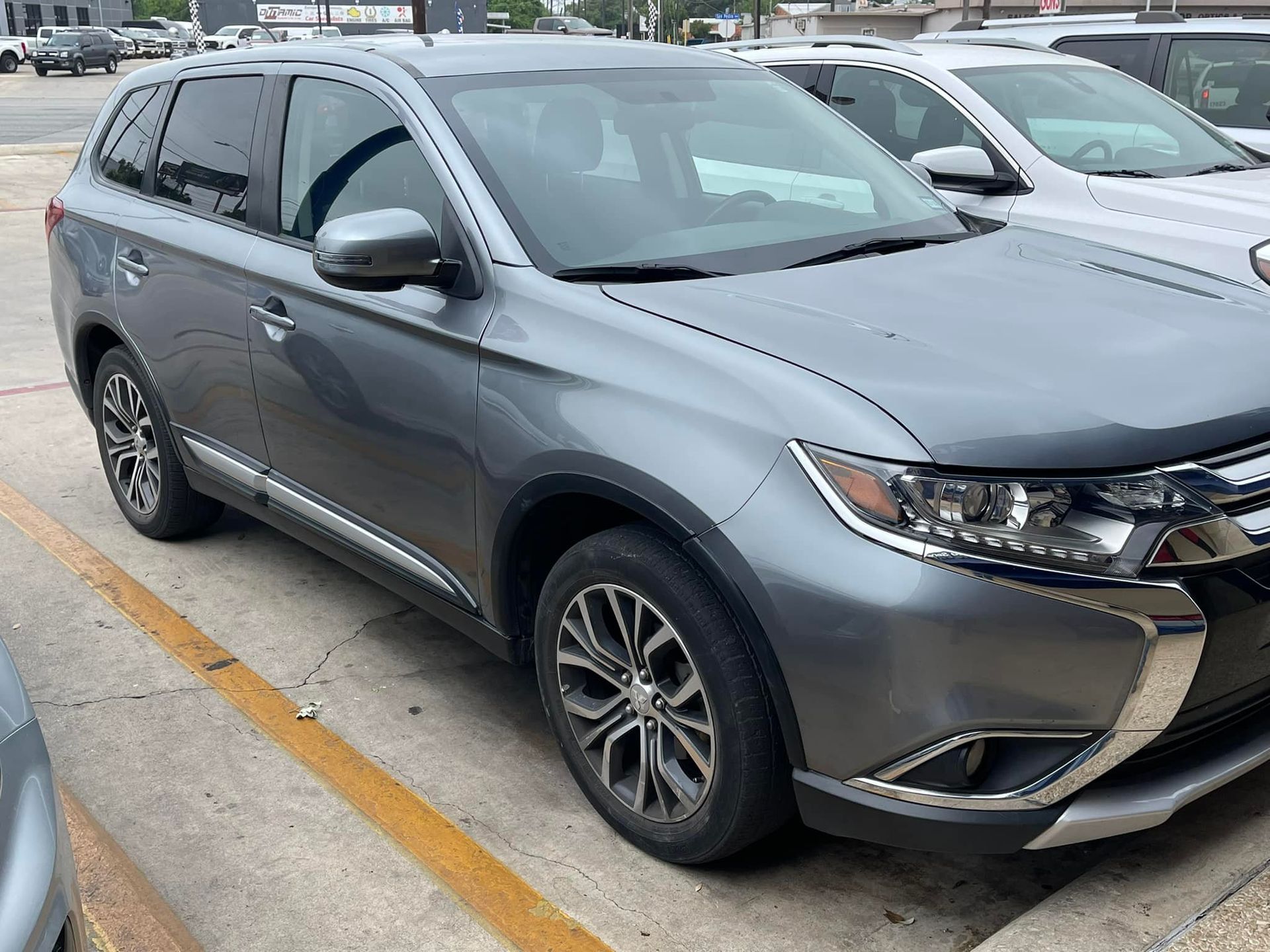 A gray suv is parked in a parking lot next to a white suv.