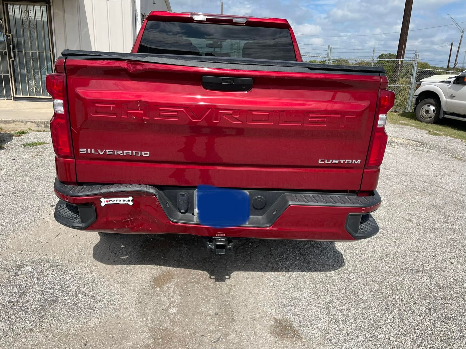 A red chevrolet truck is parked in a gravel lot.