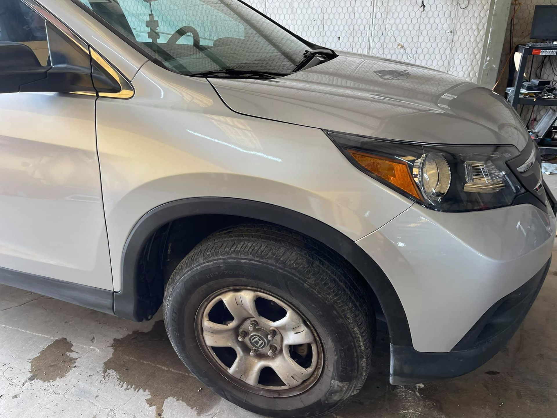 A silver car with a black tire is parked in a garage.