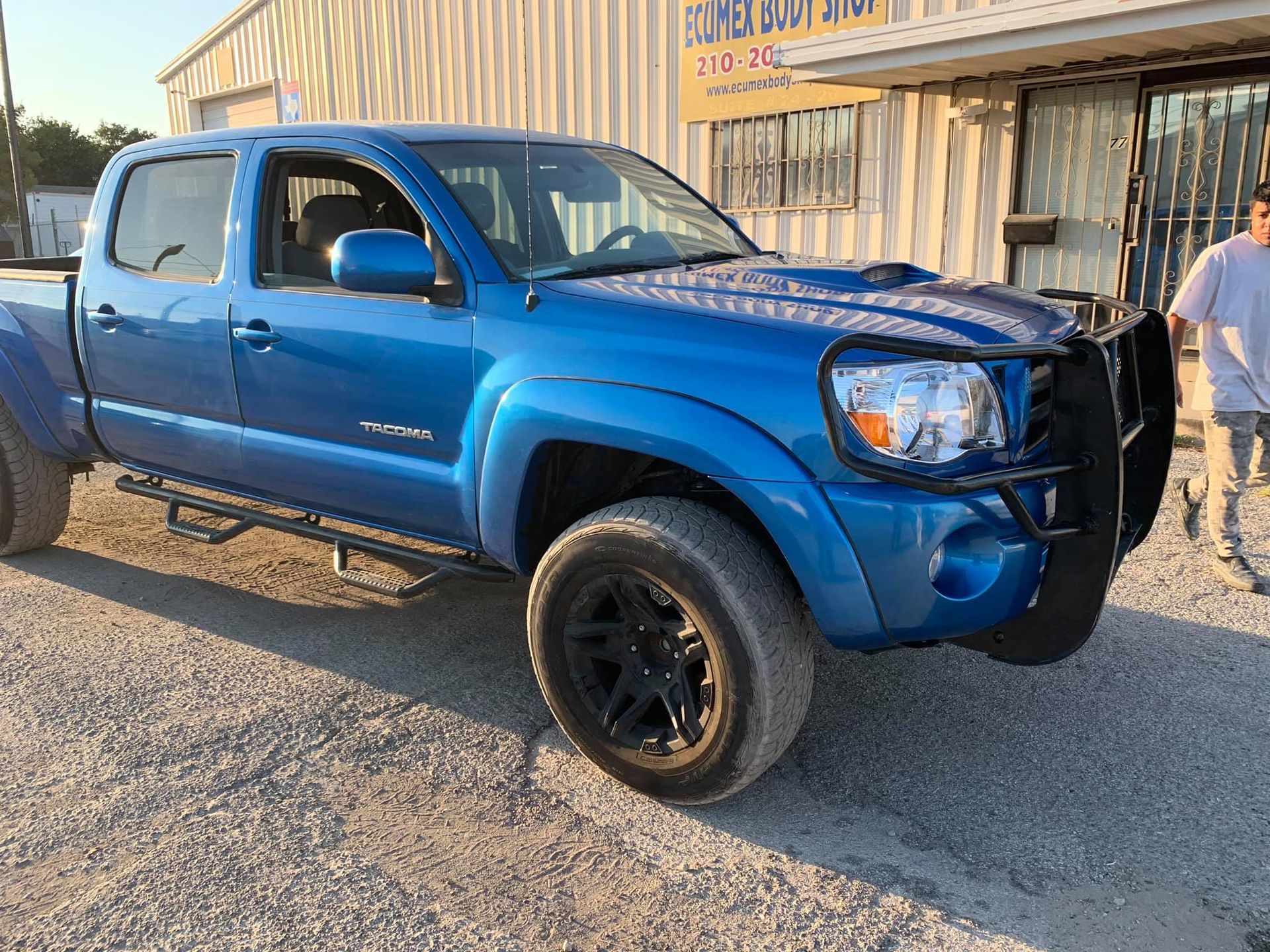 A blue truck is parked in front of a building.