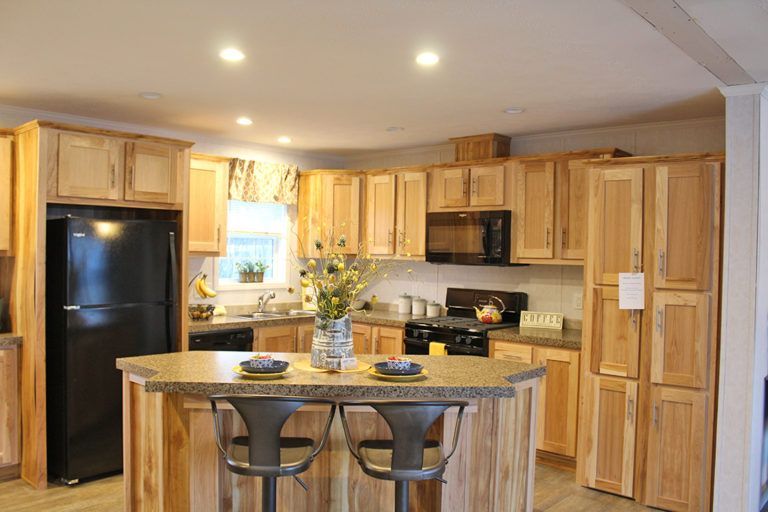 A kitchen with wooden cabinets , a black refrigerator , a stove , and a large island.