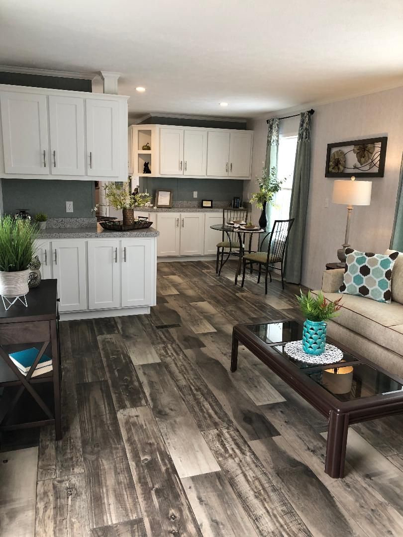 A living room with a couch , coffee table , chairs and a kitchen.