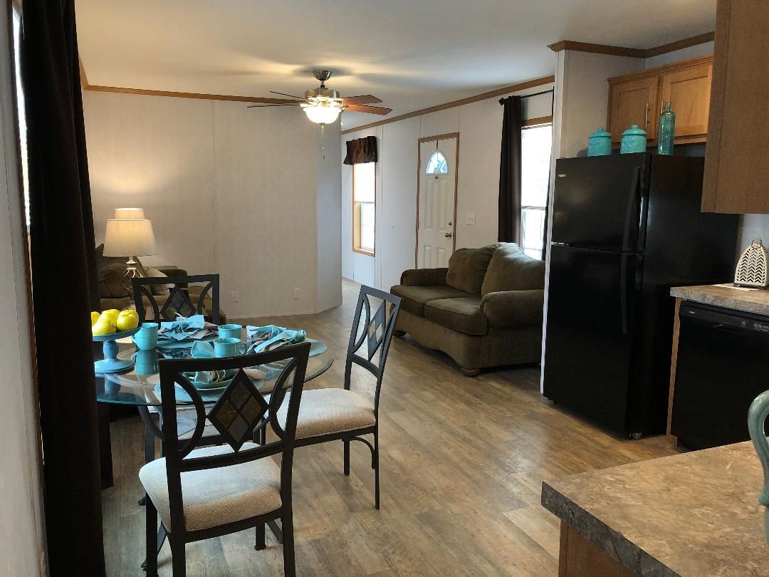 A living room with a dining table , chairs , a couch and a refrigerator.