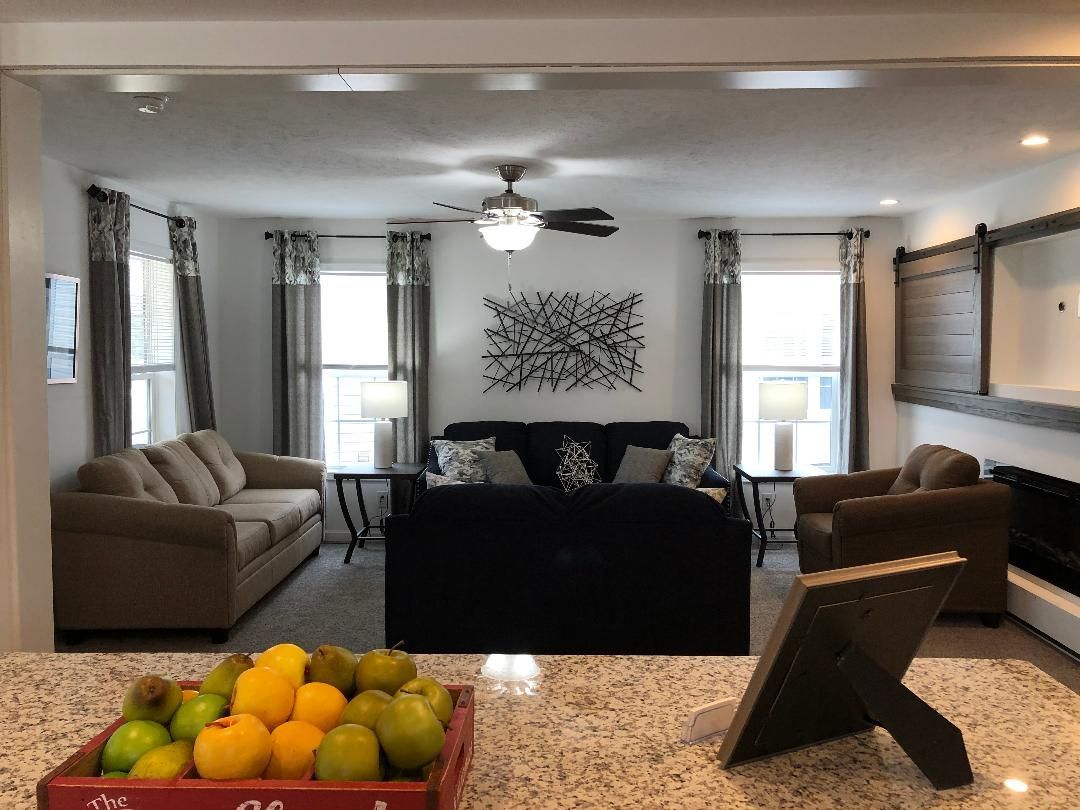 A living room with a couch , chairs and a ceiling fan