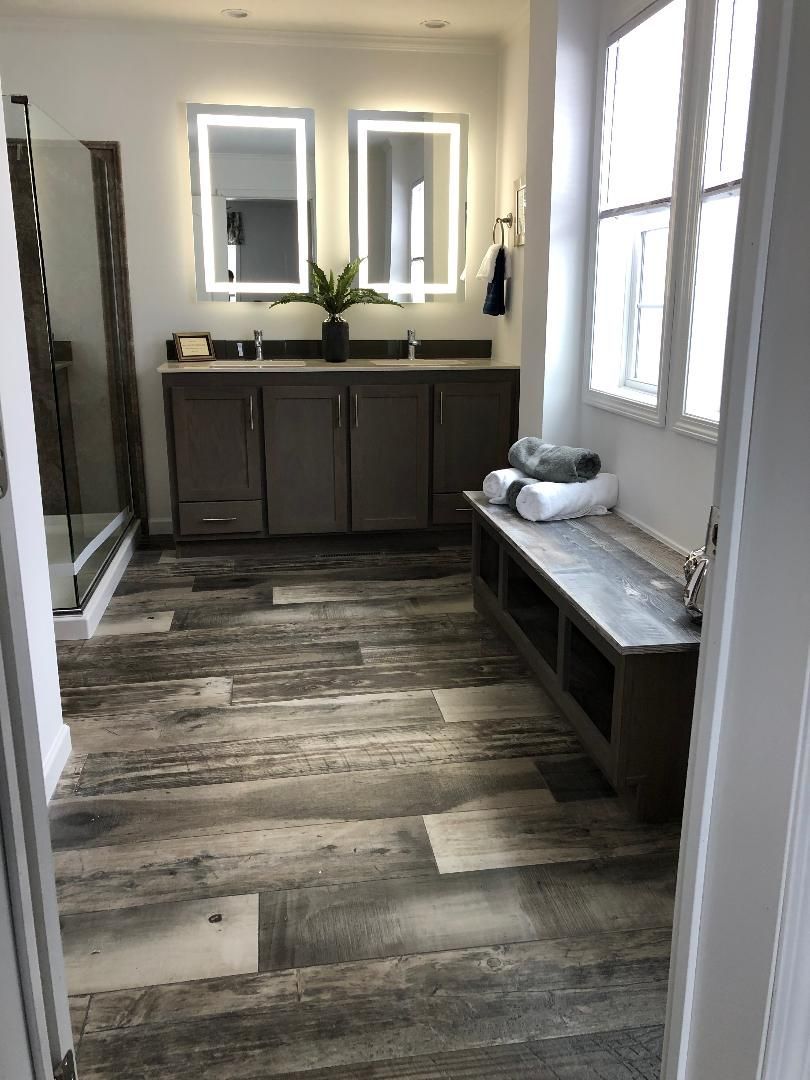 A bathroom with two sinks , two mirrors and a bench.