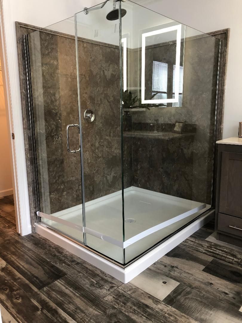 A bathroom with a walk in shower and a mirror.