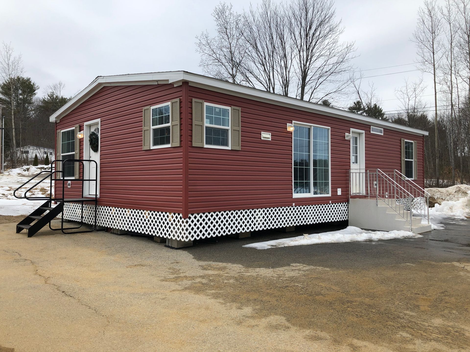 A red mobile home with stairs is sitting in the middle of a snowy field.