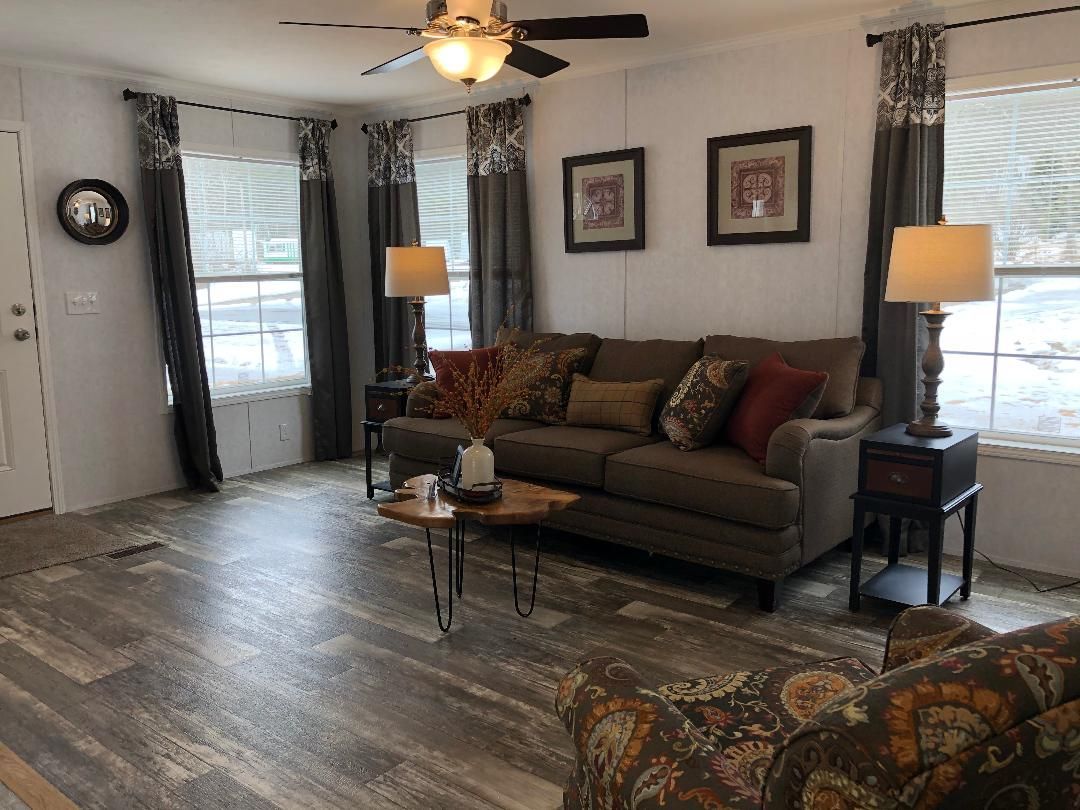 A living room with a couch , chairs , lamps and a ceiling fan.