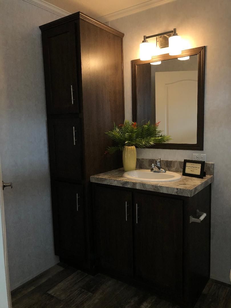 A bathroom with a sink , mirror and cabinets