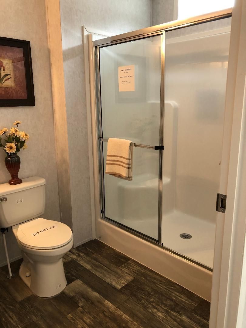 A bathroom with a toilet , shower and a picture on the wall.