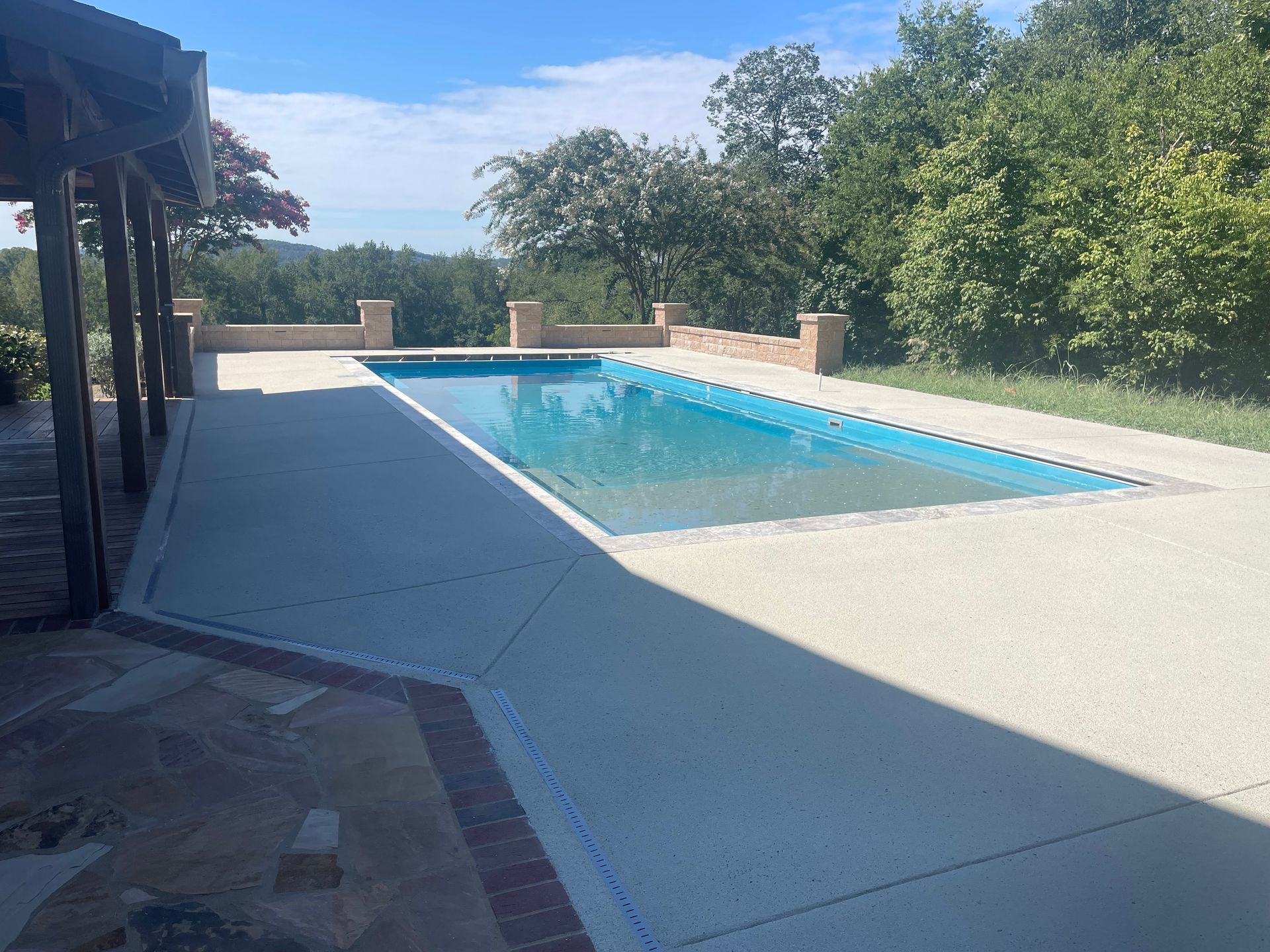 a large swimming pool is surrounded by trees on a sunny day.