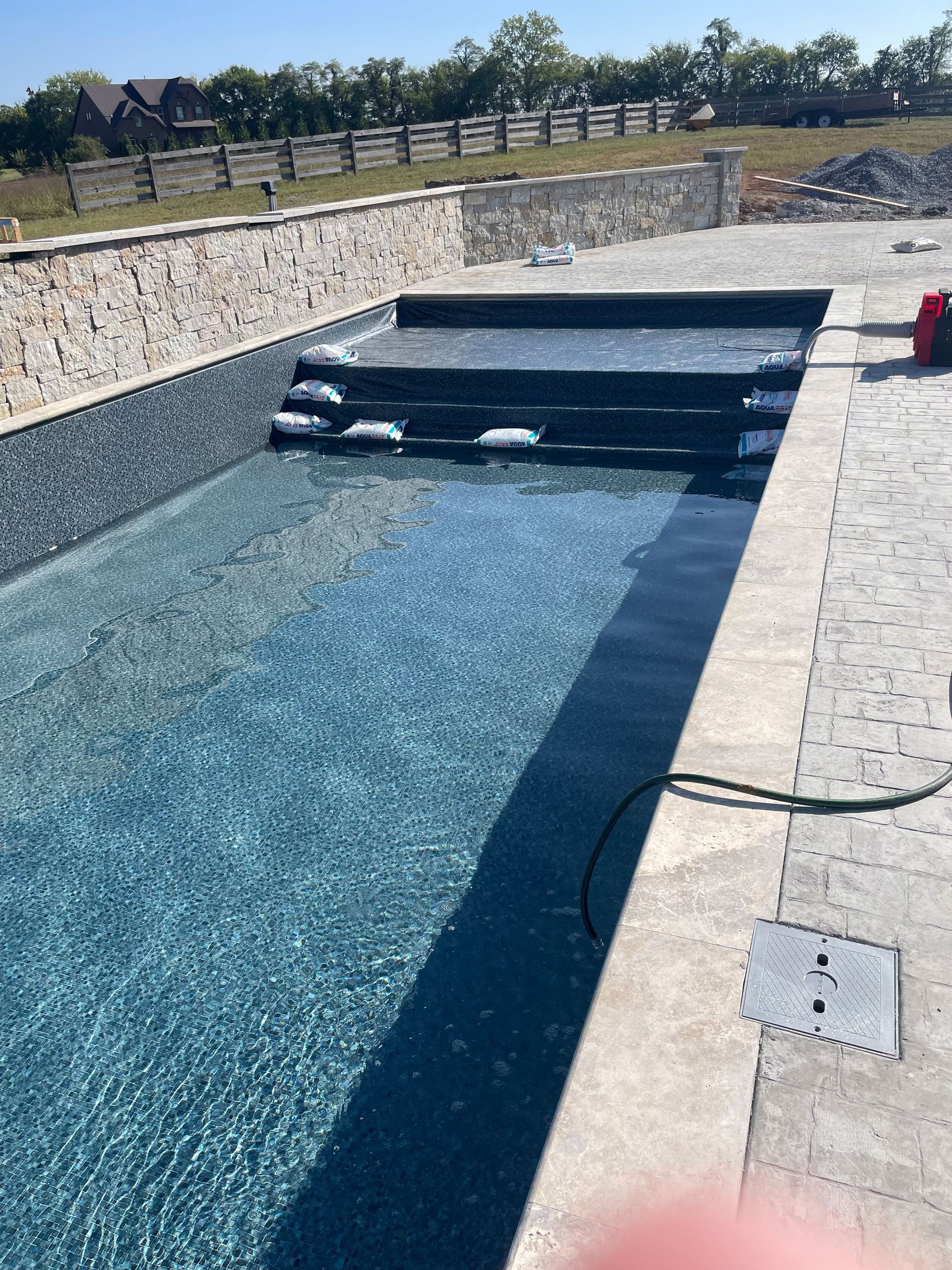 a large swimming pool with stairs and a fence in the background