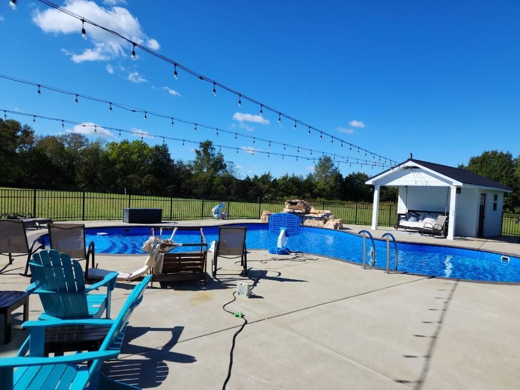 a large swimming pool is surrounded by chairs and a table.