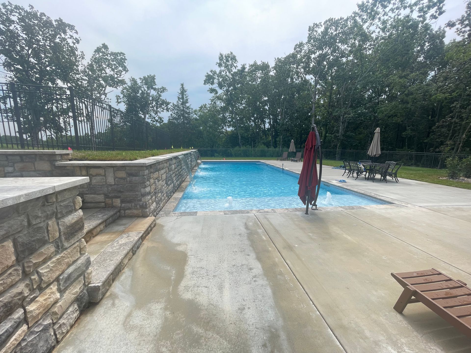 a large swimming pool with a red umbrella in the middle of it.